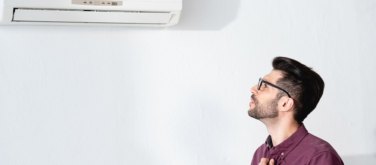 Man with glasses staring at air conditioner