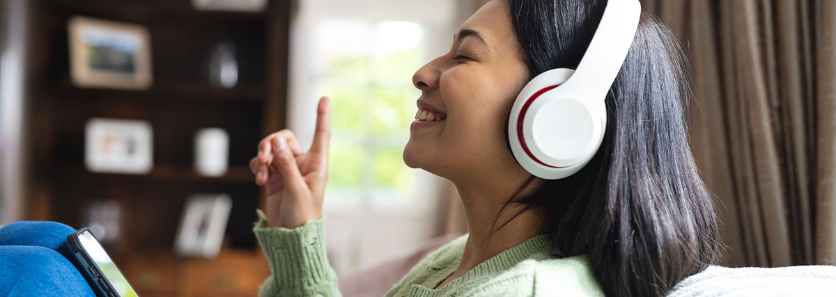 Woman listening to songs with headphone on sofa